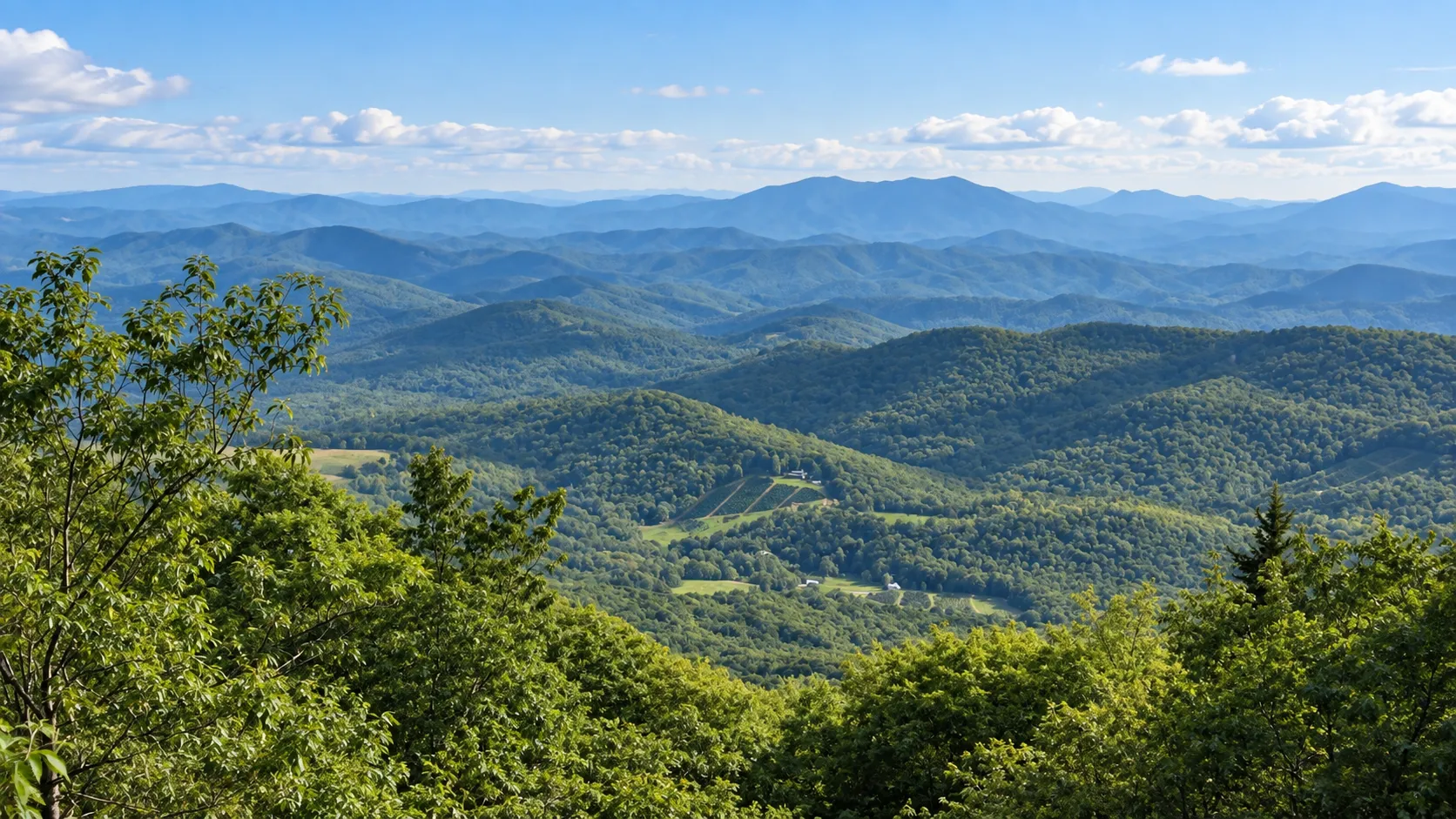 Wooded ridges receding into haze under a summer sky
